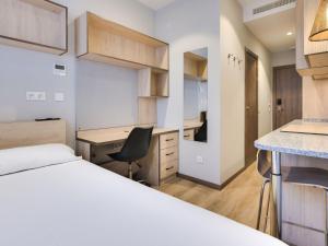 马拉加Livensa Living Studios Málaga Feria的一间卧室，配有一张床、一张桌子和一把椅子
