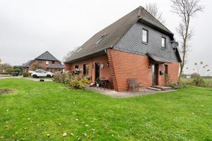 ein Backsteinhaus mit einem grasbewachsenen Hof davor in der Unterkunft Ferienwohnung Norderwurth in Büsumer Deichhausen