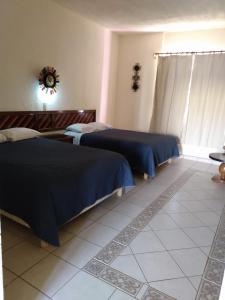 a bedroom with two beds and a tiled floor at The Halfway Inn in Guerrero Negro