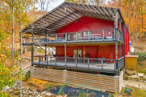 a red house with a balcony on the side of it at Games and Fire Pit Waterfront Beaver Lake Home! in Garfield