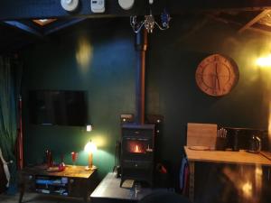 a room with a stove and a clock on the wall at Shed Gwely in Govilon