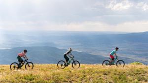 three people riding bikes on top of a hill at Western Lodge in Steamboat Springs