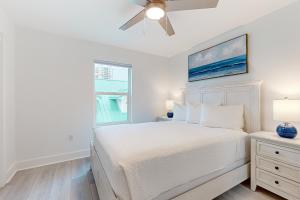 a white bedroom with a bed and a ceiling fan at Bahia Beauty - 3rd Floor in Navarre