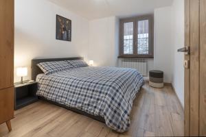 ein Schlafzimmer mit einem Bett mit einer karierten Decke in der Unterkunft Anni - AffittiPontediLegno in Temù