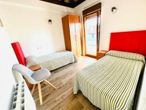a bedroom with two beds and a chair in it at Apto Pedreña Golf y Surf in Pedreña