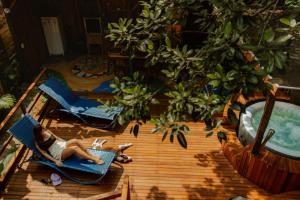 a woman laying on a chair on a wooden table at Surfway Ilha do Mel in Ilha do Mel