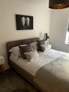 a bedroom with a large bed with white sheets and pillows at Lovely 1 bedroom top floor flat at Chocolate Quarter near city of Bath in Keynsham