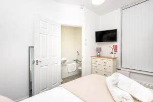 a white bedroom with a bed and a bathroom at Velvet Coaster Apartments in Blackpool