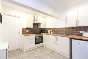 a kitchen with white cabinets and a sink at Velvet Coaster Apartments in Blackpool