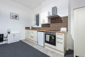 a kitchen with white cabinets and a stove top oven at Velvet Coaster Apartments in Blackpool