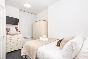 a white bedroom with a bed and a dresser at Velvet Coaster Apartments in Blackpool