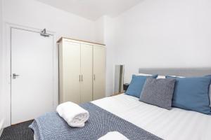 a bedroom with a bed with blue and white pillows at Velvet Coaster Apartments in Blackpool