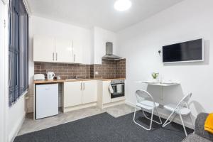 a kitchen with white cabinets and a table and chairs at Velvet Coaster Apartments in Blackpool