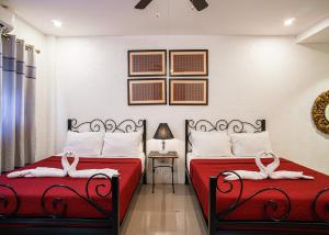 two beds in a bedroom with red sheets and white pillows at Ilocos Urban Wave Resort Hotel in Laoag +48 photos