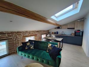 a living room with a green couch and a brick wall at L'Escale in Grisolles