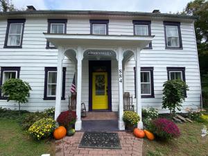 a white house with a yellow door and pumpkins at Trouvaille House Sweet Suite in Harpers Ferry +10 photos
