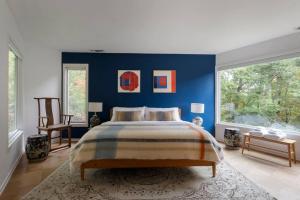 Un dormitorio con una cama y una pared azul. en Quarry House Mid-Century Modern, en Haddam
