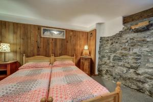 a bedroom with a bed and a stone wall at Alpine Essence, typical mountain style apartment CIR AYAS0036 in Champoluc