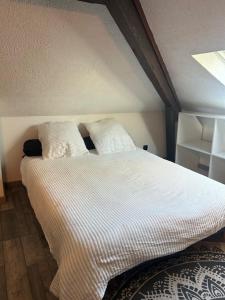 Una cama con sábanas blancas y almohadas en una habitación. en LE VICTORIA, en Besançon