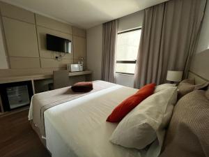 a hotel room with a white bed with red pillows at Comfortable Flat 807 in the Center of Três Rios in Três Rios