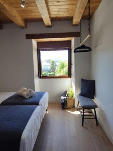 a bedroom with a bed and a chair and a window at Casa Rural El Pinche in Quincoces de Yuso