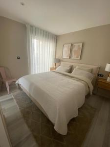 a bedroom with a large white bed and a window at Casa Janna in Cabo Roig +29 photos