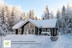a house covered in snow in front of trees at Lähderinne - 2 bedroom log cabin, private beach, wifi & sauna in Puolanka