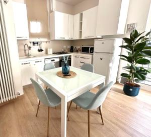 a white kitchen with a white table and chairs at Casa Sofia in Bologna