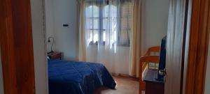 a bedroom with a blue bed and a window at La Elvira in San Antonio de Areco