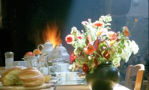 una mesa con un jarrón lleno de flores y pan en La Grange de Coatélan, en Plougonven