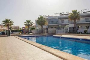 una piscina frente a un edificio con palmeras en Bungalow Pink Oasis - Winter by the Sea, en Alicante