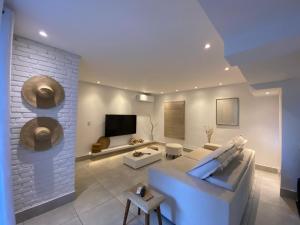 ein Wohnzimmer mit einem weißen Sofa und einem Fernseher in der Unterkunft Casa de férias in Balneário Camboriú