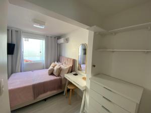 ein Schlafzimmer mit einem Bett, einem Schreibtisch und einem Spiegel in der Unterkunft Casa de férias in Balneário Camboriú