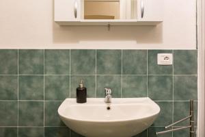 Baño con lavabo blanco y azulejos verdes en Holiday Home Naiadis, en Roma