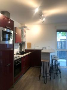 a kitchen with red cabinets and a counter with stools at Appartement touristique Clisson gare in Clisson