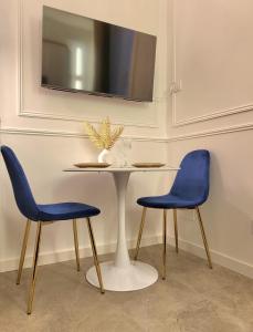 a table with two blue chairs and a tv at Studio élégant Presqu'île Lyon 1er in Lyon +16 photos