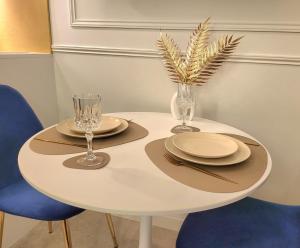 a white table with two chairs and plates and glasses at Studio élégant Presqu'île Lyon 1er in Lyon