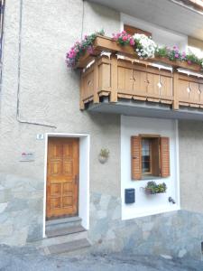 un edificio con porta in legno e balcone fiorito di Casa Elda a Valdidentro