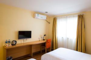 a bedroom with a desk with a television and a window at Home Inn Shanghai Jin'gao Road North Yanggao Road Metro Station in Shanghai