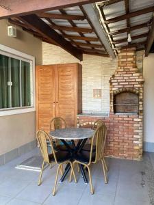 - une table et des chaises sur une terrasse avec un four en briques dans l'établissement Casa aconchegante em Aquarius, à Cabo Frio