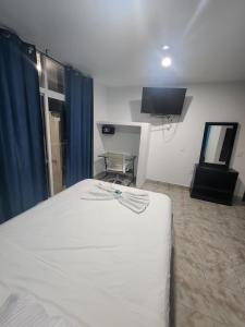 a bedroom with a white bed and a television at Hotel Turquesa in Playa del Carmen