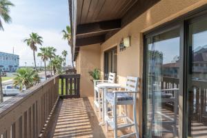 einen Balkon mit zwei Stühlen und einem Tisch darauf in der Unterkunft Tiki 250 in South Padre Island