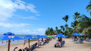 a group of people sitting under blue umbrellas on a beach at Pousada Du’Forte in Praia do Forte