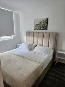 a bed in a bedroom with a large headboard at Apartaestudio FANTASTICO UBICADO EN EL NORTE DE ARMENIA CERCA A LOS PUEBLOS Y AL PARQUE DEL CAFE in Armenia