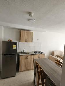 a kitchen with a stainless steel refrigerator and a table at Apartaestudio FANTASTICO UBICADO EN EL NORTE DE ARMENIA CERCA A LOS PUEBLOS Y AL PARQUE DEL CAFE in Armenia
