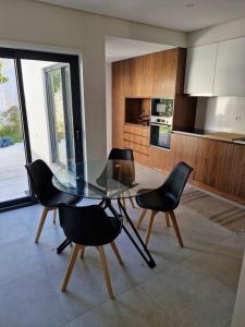 a dining room with a glass table and black chairs at Casa Francisca praia de Mindelo in Mindelo