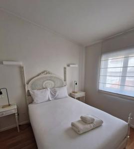 a bedroom with a white bed with two towels on it at Casa Francisca praia de Mindelo in Mindelo