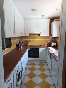 Alcolea de CincaにあるCasa Carmenの白いキャビネットとチェッカーフロア付きのキッチン