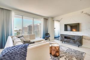 a living room with a white couch and a tv at Steps to Fort Lauderdale Beach Oceanfront Condo in Fort Lauderdale