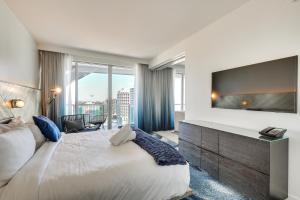 a hotel room with a large bed and a large television at Steps to Fort Lauderdale Beach Oceanfront Condo in Fort Lauderdale +18 photos